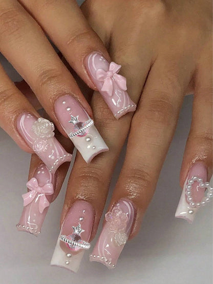 Elegant 24-piece XL square press-on nails featuring a pink and white design with 3D bows, pearls, and rhinestone accents for a glamorous manicure.