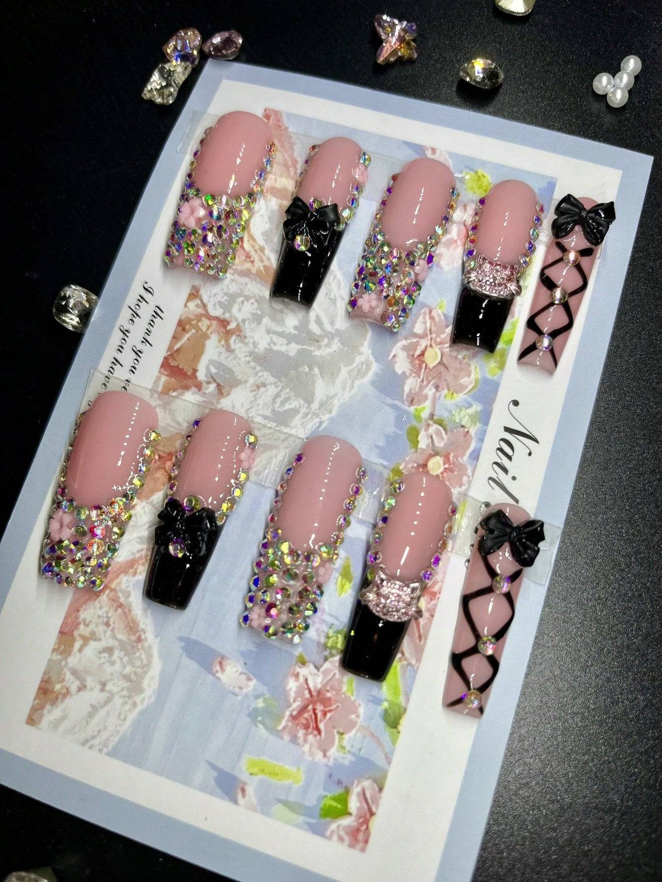 XL press-on nails with designs featuring pink and black tones, adorned with 3D rhinestones, floral motifs, bowknots, and lattice patterns for a glamorous look.