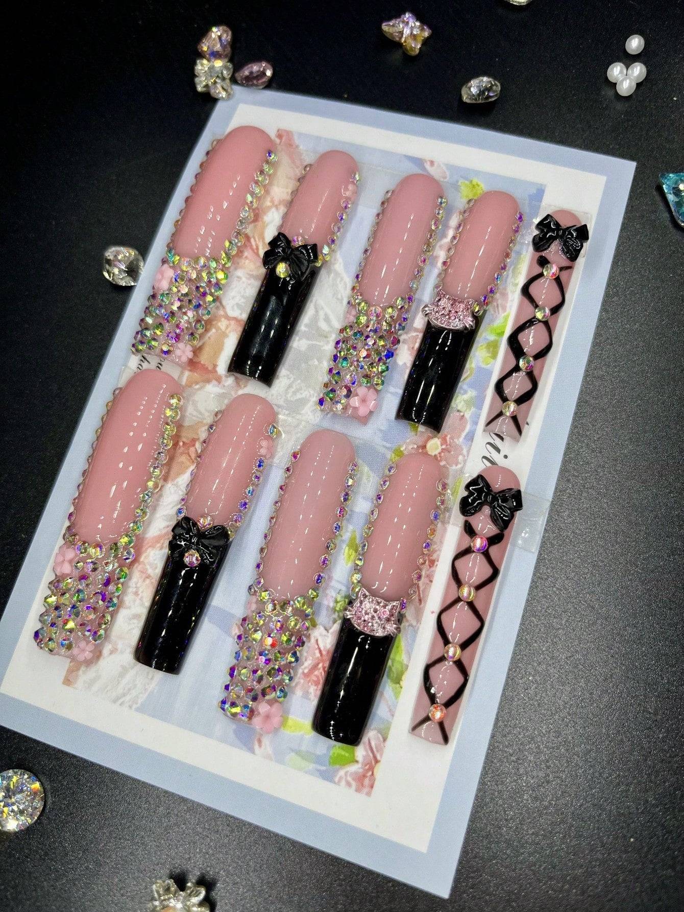 XL press-on nails with designs featuring pink and black tones, adorned with 3D rhinestones, floral motifs, and bowknots for a glamorous look.