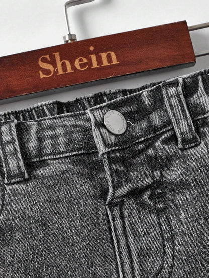 Waistband and button detail of kids' black denim jeans, featuring an elastic back for a comfortable and adjustable fit.