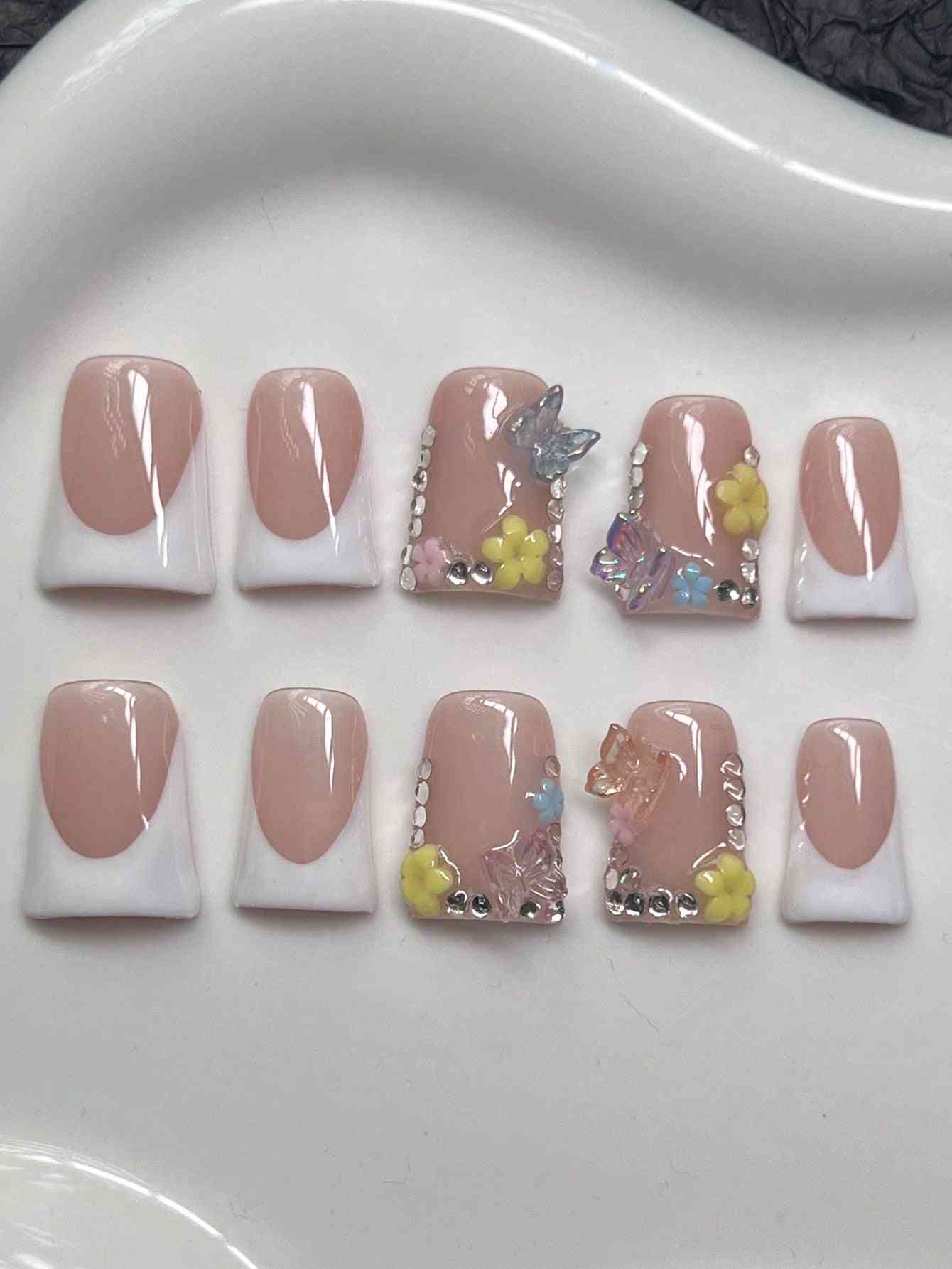 Y2K Duck Nail Tips with floral and rhinestone designs in nude and white tones. These press-on false nails feature butterfly and gem embellishments.