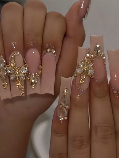 Elegant 24-Piece XL Square Press-On Nails featuring a nude base with intricate gold and crystal embellishments. Luxurious extra-long design for a glamorous look.