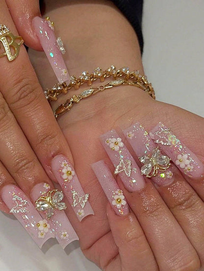 Elegant 24-Piece XL Square Press-On Nails featuring a pink glitter base with intricate floral and butterfly embellishments. These luxury extra-long false nails provide a flawless, full-cover manicure with a glamorous and artistic design.