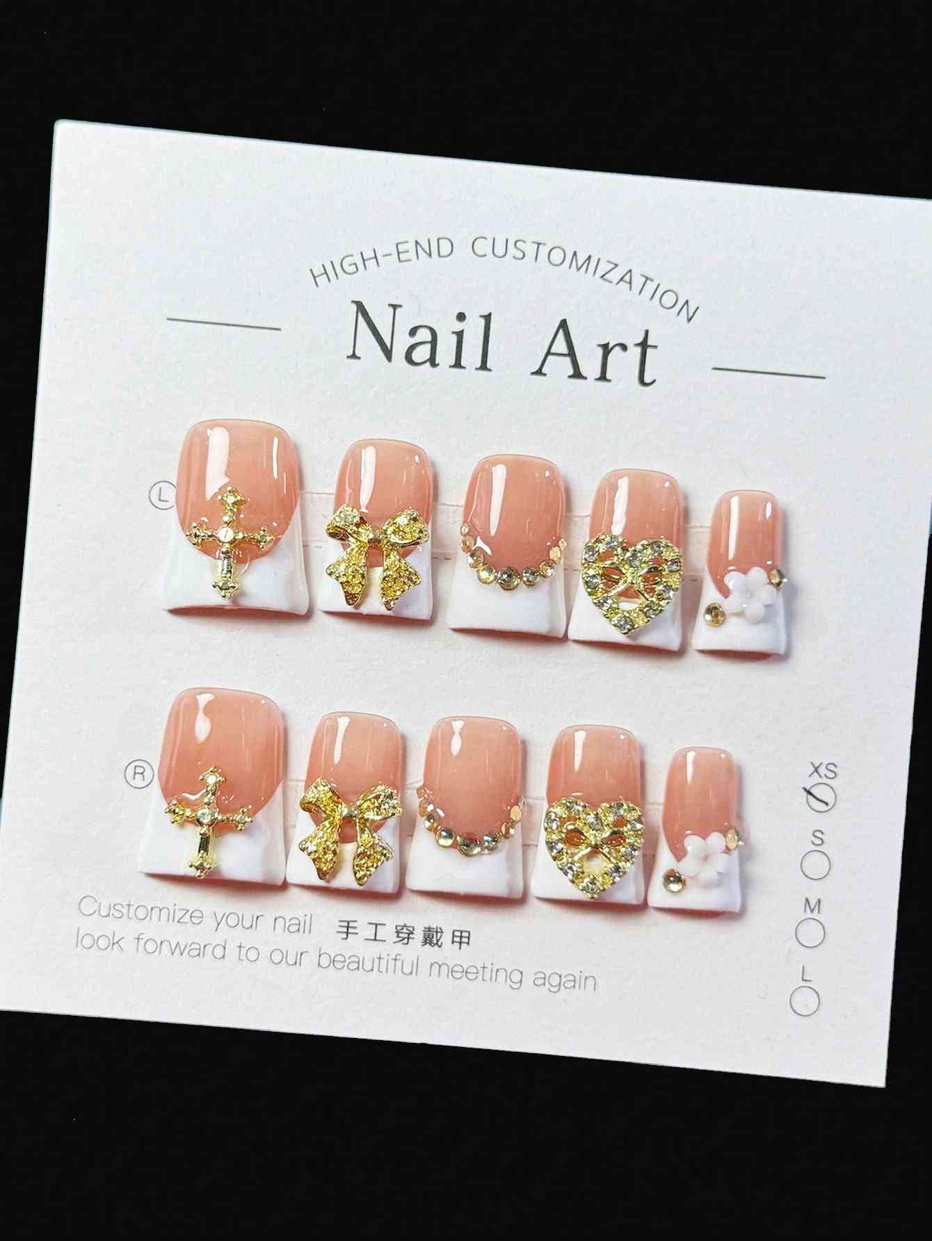 Elegant white French oval fake nails with gold embellishments, featuring intricate bows, hearts, and pearl accents. A luxury 10-piece press-on nail set.