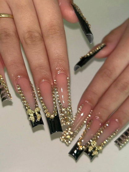 Elegant 24-Piece XL Square Press-On Nails featuring a luxurious black and gold design with rhinestone embellishments and 3D bow accents for a glamorous look.