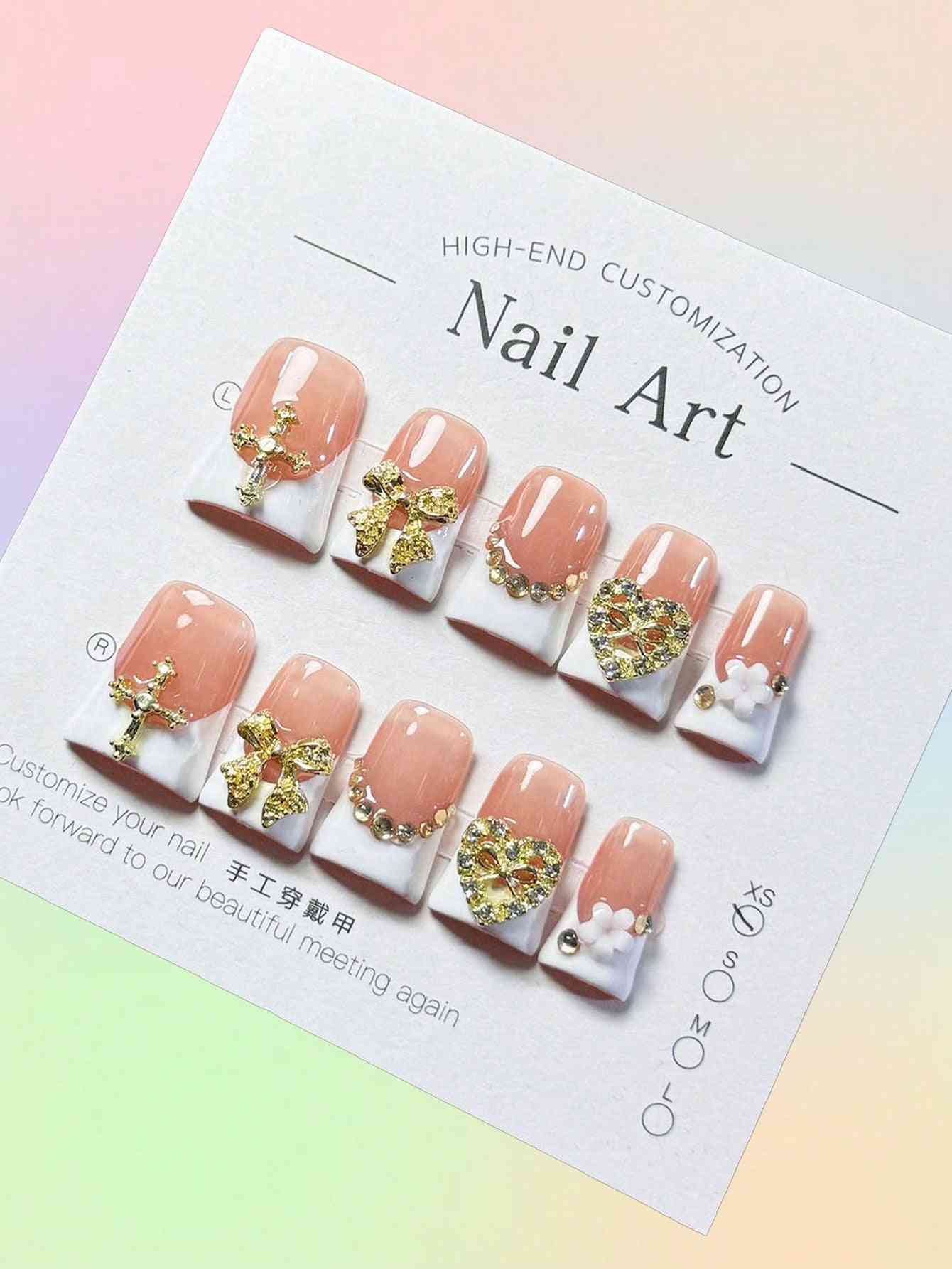 Elegant white French oval fake nails with gold embellishments, featuring intricate bows, hearts, and pearl accents. A luxury 10-piece press-on nail set.