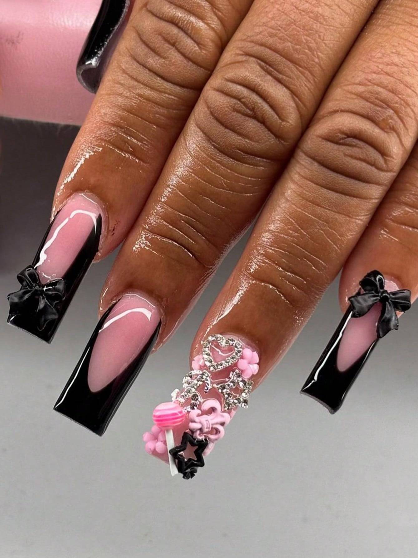 Elegant 24-piece XL square press-on nails featuring a black French tip design with pink and 3D embellishments, including bows and rhinestones.